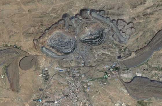 A picture showing an open-pit mining site with east and west stope surrounded by waste dump like demon’s claws and teeth